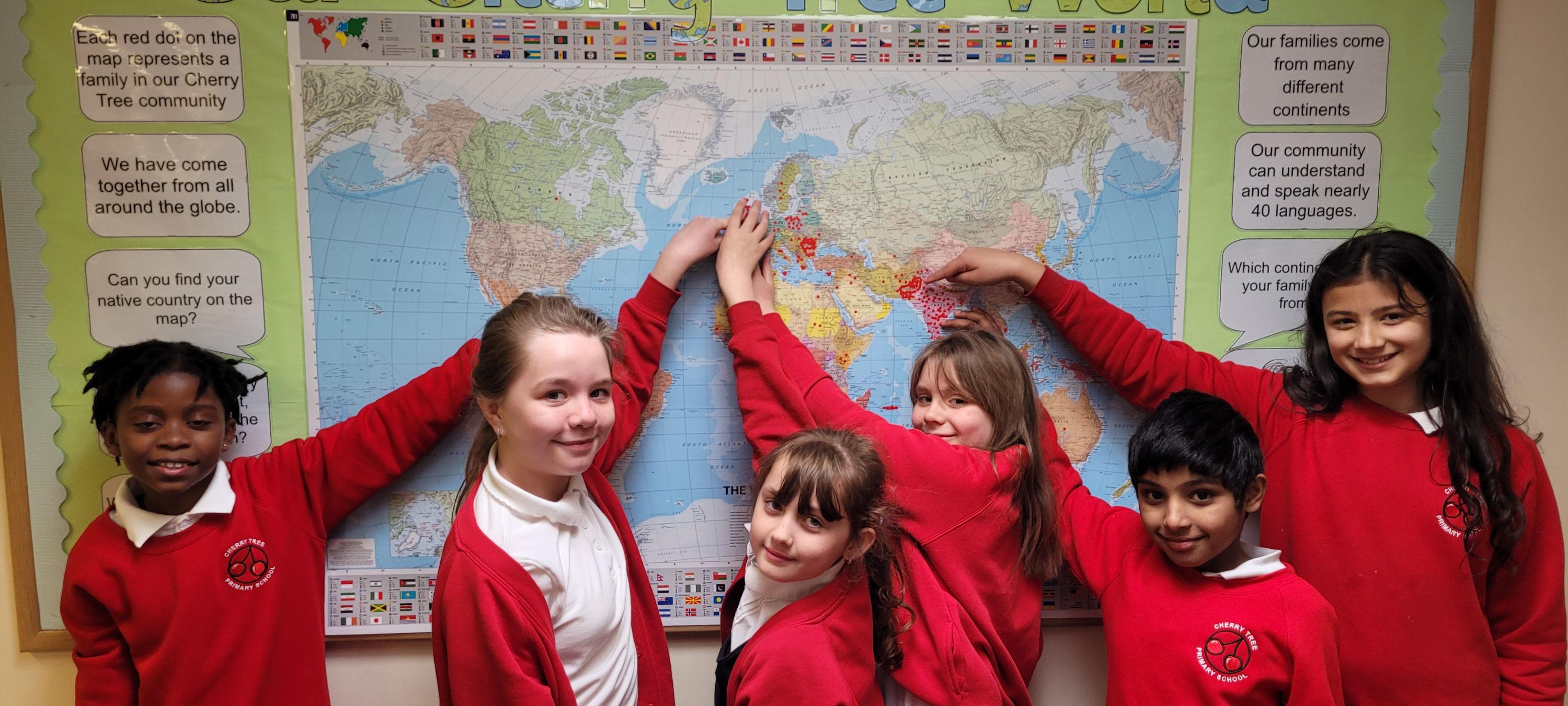 pupils point at places on a world map in a school corridor