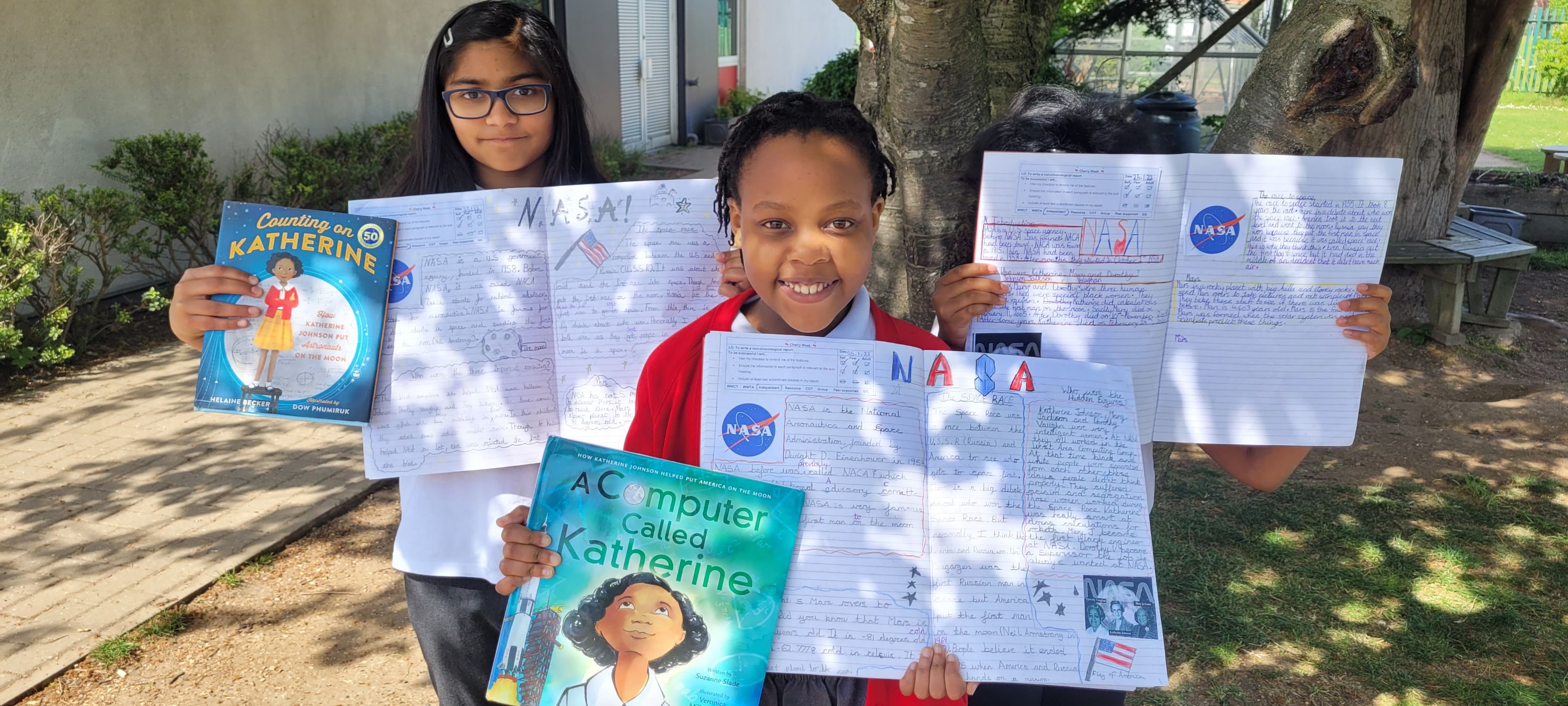 pupils hold up their history books outside in the sunshine