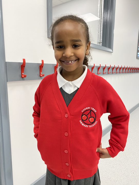 student stands in corridor wearing red school cardigan 