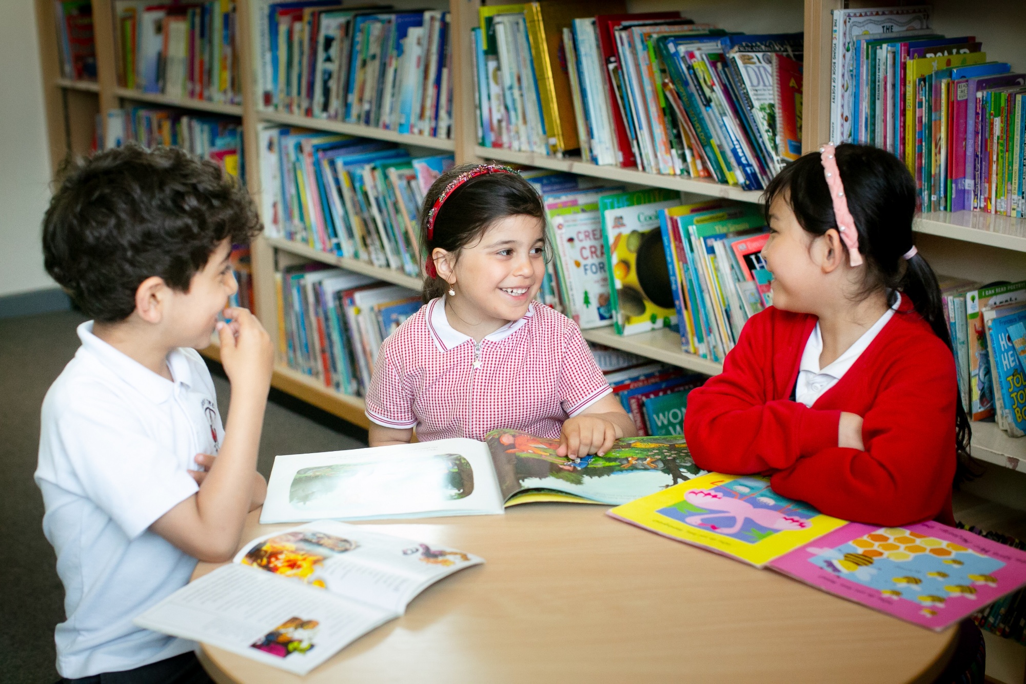3 pupils look at books together in the library